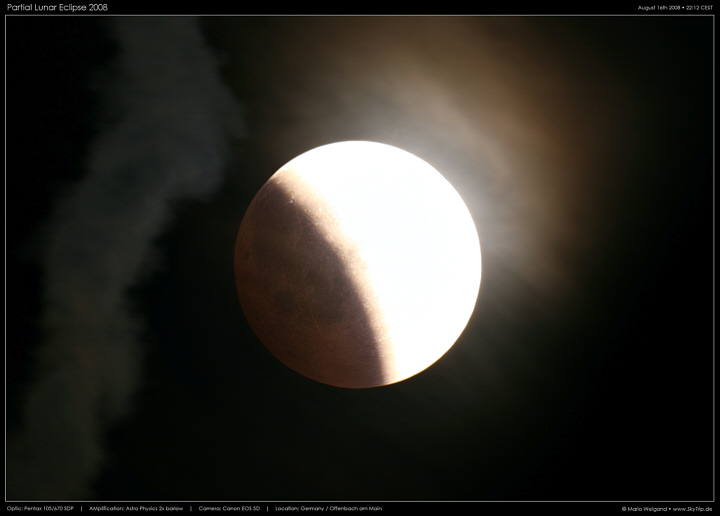 Foto der partiellen Mondfinsternis 2008 mit leichter Zirrusbewlkung und Kondensstreifen.